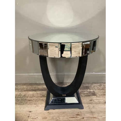 179 - A mirrored occasional table of circular outline on a black u-shaped support, mirrored and black plin... 