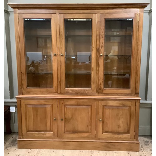 408 - A fruitwood breakfront bookcase having three bevelled glazed doors above a base with three doors, on... 