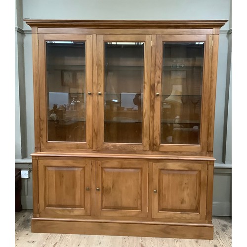 408 - A fruitwood breakfront bookcase having three bevelled glazed doors above a base with three doors, on... 