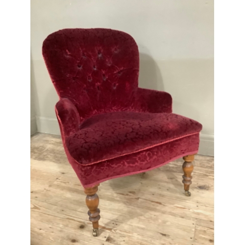 453 - A Victorian walnut button back nursing chair in red velvet fabric on turned legs with brass casters