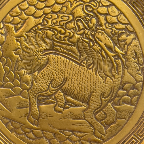 75 - A Chinese polished bronze charger, engraved to the centre with a dragon within a geometric band, bor... 