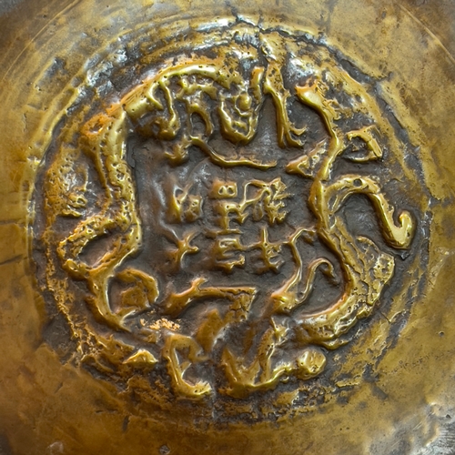 75 - A Chinese polished bronze charger, engraved to the centre with a dragon within a geometric band, bor... 