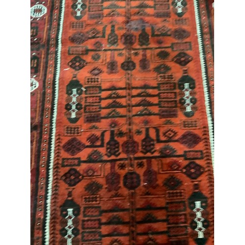 459 - An Afghan rug, the burnt orange ground filled with rows of stylised plan forms, within a wine, burnt... 