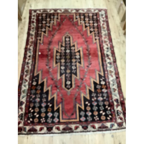 457 - A Persian Hamadham Maslaghan rug, the deep pink ground with dark brown stepped medallion and spandre... 