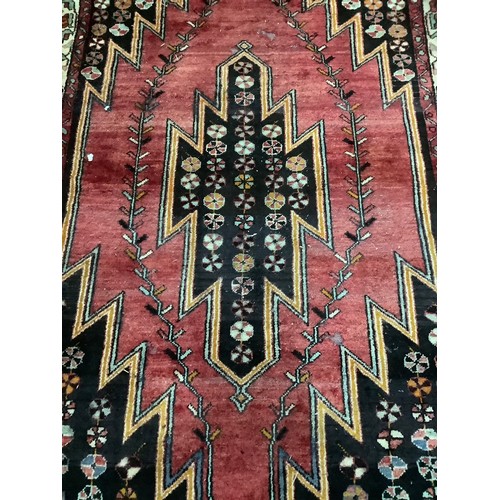 457 - A Persian Hamadham Maslaghan rug, the deep pink ground with dark brown stepped medallion and spandre... 