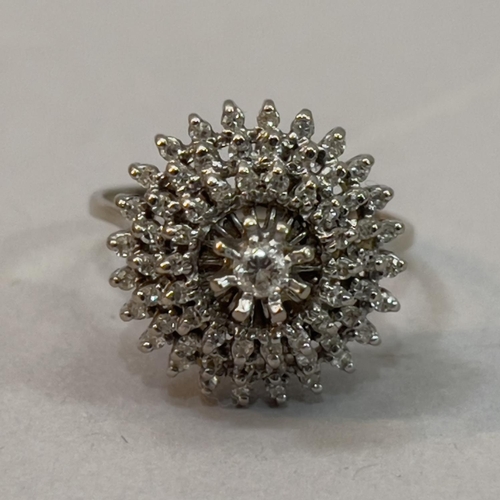 213 - A diamond cluster ring, claw set to the centre with brilliant cut stone raised against a tiered surr... 