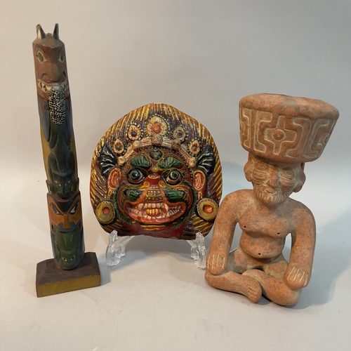 25 - A Nepalese papier mache face mask painted in bright colours, a Mayan clay figure of a god seated and... 