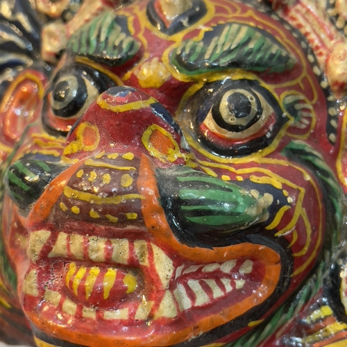 25 - A Nepalese papier mache face mask painted in bright colours, a Mayan clay figure of a god seated and... 