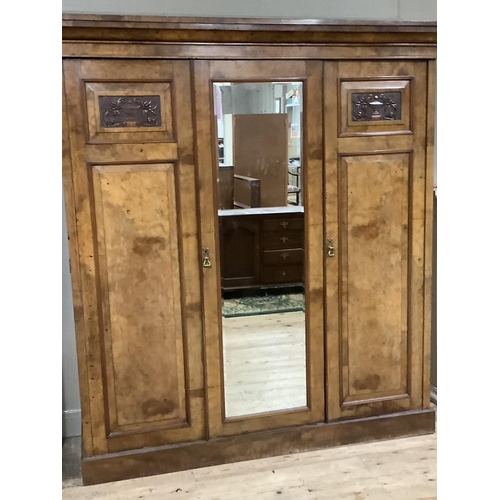 273 - A Victorian walnut triple wardrobe with carved cartouches, pediment top, central mirrored door, fitt... 