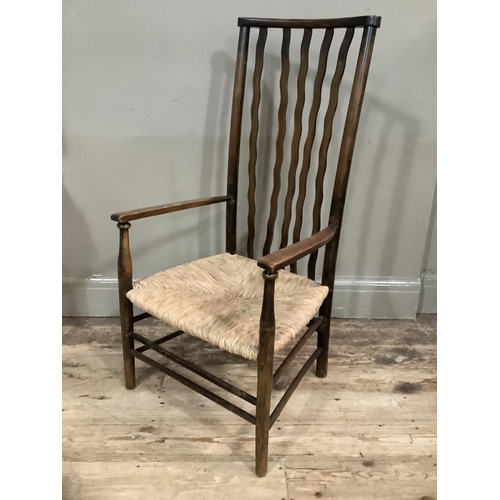 278 - An Arts and Crafts style mahogany nursing chair with waved back on rush seat