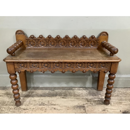 280 - An oak hall bench with bobbin arms and legs, heavily carved back and carved apron