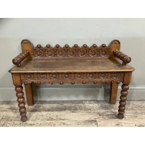 280 - An oak hall bench with bobbin arms and legs, heavily carved back and carved apron