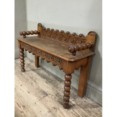 280 - An oak hall bench with bobbin arms and legs, heavily carved back and carved apron