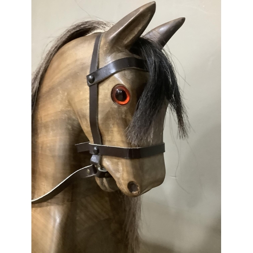 262 - A fruitwood carved rocking horse with leather reigns and saddle with horse hair mane and tail, 163cm... 