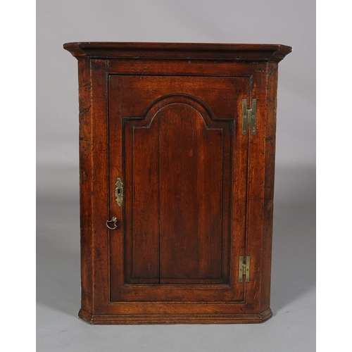 230 - AN EARLY 19TH CENTURY OAK HANGING CORNER CUPBOARD, having a moulded cornice above a single door with... 