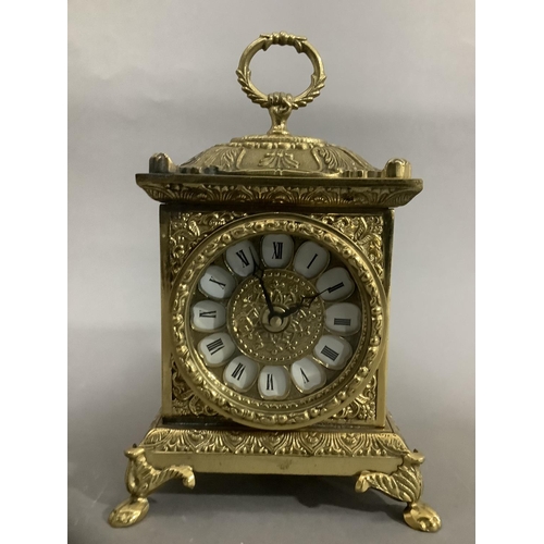 19 - An ornate brass mantel clock with foliate moulding on paw feet with quartz movement, 23cm high