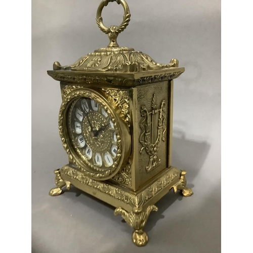 19 - An ornate brass mantel clock with foliate moulding on paw feet with quartz movement, 23cm high