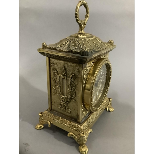 19 - An ornate brass mantel clock with foliate moulding on paw feet with quartz movement, 23cm high