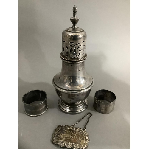 178 - A silver plate on copper sugar sifter, two George V silver napkin rings and a George V spirit label