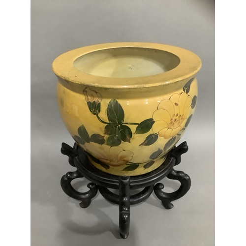 125 - A ceramic jardiniere in mustard glaze painted with flowers on carved hardwood stand, 25cm high