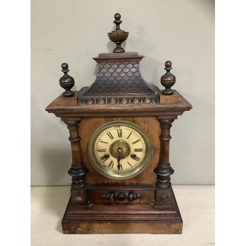 127 - A German heavily carved wooden clock with pitched roof and urn finials, HAC movement, enamel dial wi... 