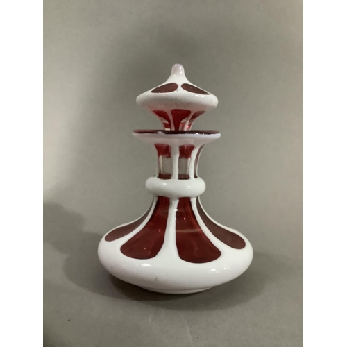 8 - A Bohemian ruby glass scent bottle with white overlay cut with roundels having a drop stopper, 11cm ... 