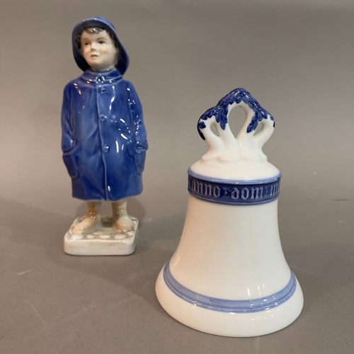 12 - A Royal Copenhagen figure of a boy in a raincoat no.532 and a Royal Copenhagen bell, 13cm high