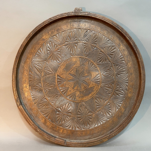 121 - A circular hardwood table top, having a heavily carved surface, with hanging to back 62cm diameter