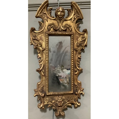 138 - A composite gilt wall mirror having a broken arch pediment, with mask finial and ornate moulding, 65... 