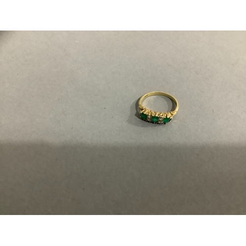 205 - A George V emerald and diamond ring in 18ct gold, the three set cut emeralds claw set in line, inter... 