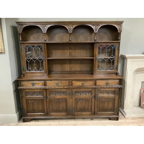 214 - An Old Charm dresser having a moulded cornice and shelf with arched frieze, above a shelf to the cen... 