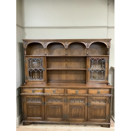 214 - An Old Charm dresser having a moulded cornice and shelf with arched frieze, above a shelf to the cen... 