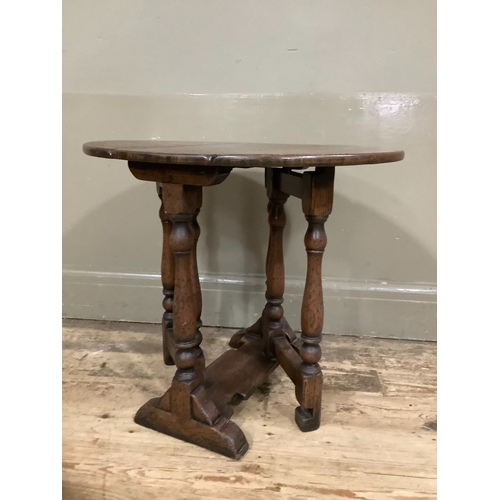 246 - An oak oval gateleg occasional table with twin drop leaf on turned legs with platform stretcher