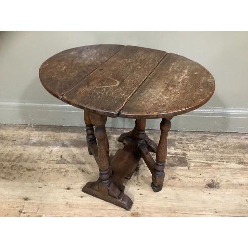 246 - An oak oval gateleg occasional table with twin drop leaf on turned legs with platform stretcher