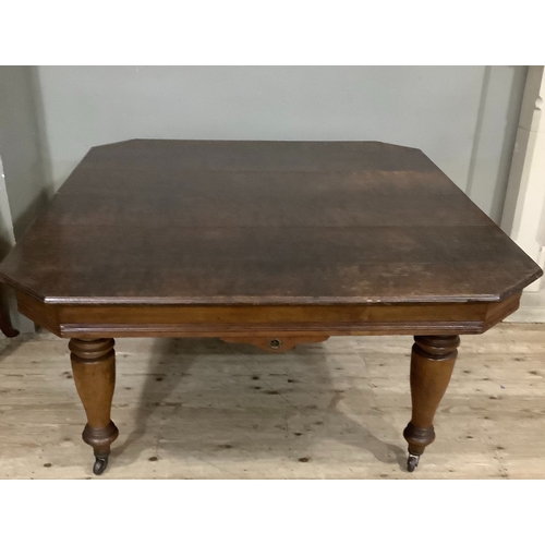 253 - An early 20th century oak extending dining table, rectangular with clipped corners, wind out mechani... 