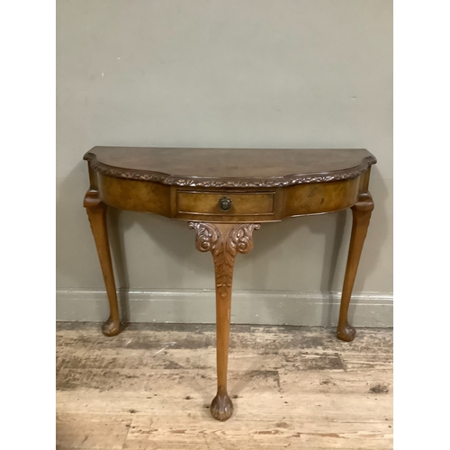 256 - Mid 20th century walnut demi-lune hall table on three cabriole legs having foliate carving to the sh... 