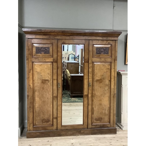 212 - A Victorian walnut triple wardrobe with carved cartouches, pediment top, central mirrored door, fitt... 