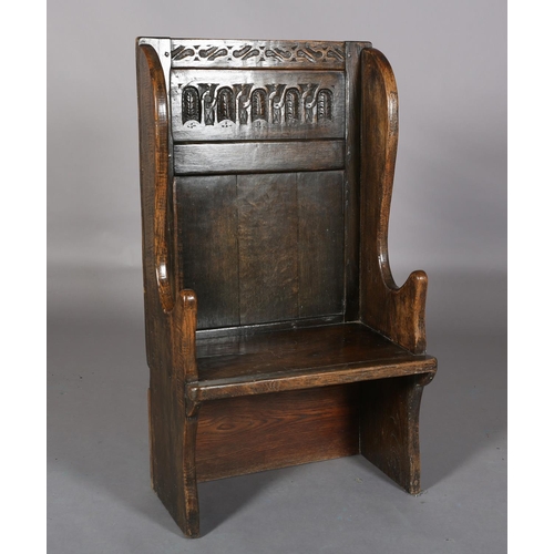 367 - AN 18TH CENTURY STYLE OAK WINGED CHAIR, the back carved with a panel of interlocking foliate filled ... 