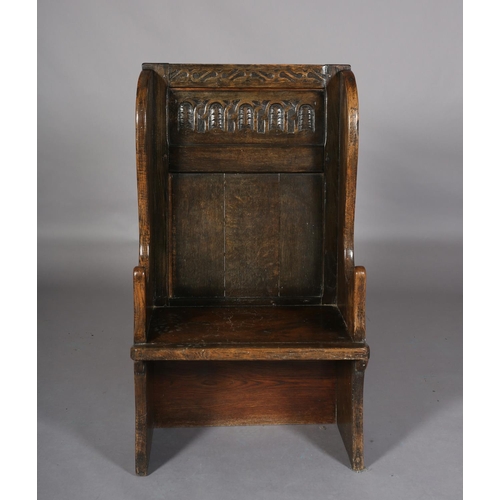 367 - AN 18TH CENTURY STYLE OAK WINGED CHAIR, the back carved with a panel of interlocking foliate filled ... 