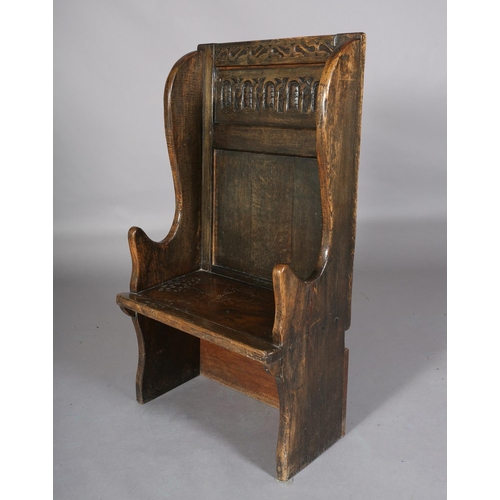 367 - AN 18TH CENTURY STYLE OAK WINGED CHAIR, the back carved with a panel of interlocking foliate filled ... 