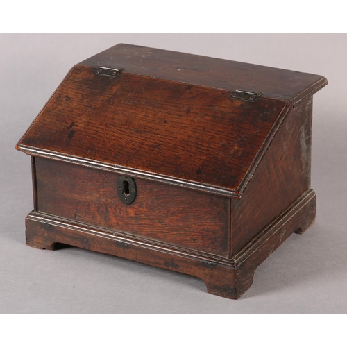 34 - AN 18TH CENTURY OAK BOX with hinged sloping lid, with brass escutcheon on bracket feet, fitted with ... 