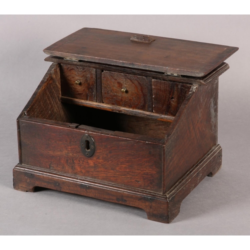 34 - AN 18TH CENTURY OAK BOX with hinged sloping lid, with brass escutcheon on bracket feet, fitted with ... 