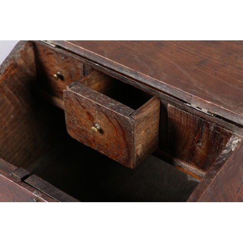 34 - AN 18TH CENTURY OAK BOX with hinged sloping lid, with brass escutcheon on bracket feet, fitted with ... 