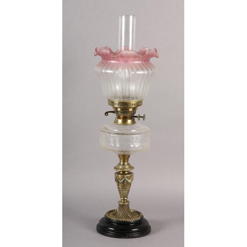 39 - A VICTORIAN BRASS OIL LAMP, clear glass reservoir, cranberry tinted opaque shade etched with flowers... 