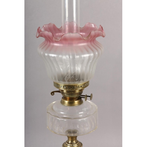 39 - A VICTORIAN BRASS OIL LAMP, clear glass reservoir, cranberry tinted opaque shade etched with flowers... 