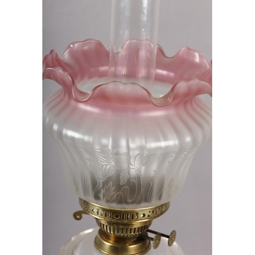 39 - A VICTORIAN BRASS OIL LAMP, clear glass reservoir, cranberry tinted opaque shade etched with flowers... 