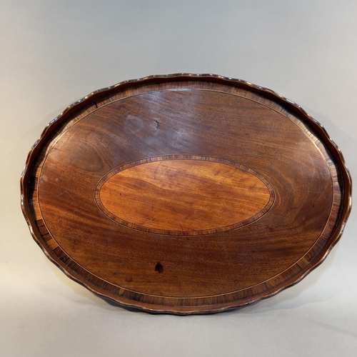 75 - AN EARLY 19TH CENTURY MAHOGANY AND ROSEWOOD CROSSBANDED OVAL TRAY, with wavy gallery, oval panel to ... 