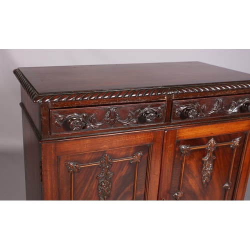 383 - A MAHOGANY CABINET, c1900, having a gadroon rim above two drawers with applied foliate scroll work a... 