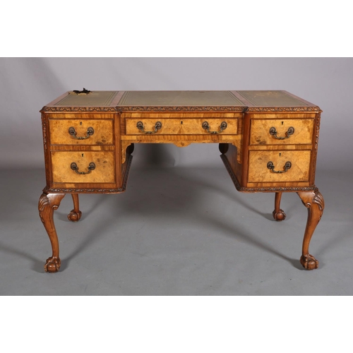 385 - AN 18TH CENTURY-STYLE FIGURED WALNUT DESK, inverted breakfront, having three incised leather panels,... 