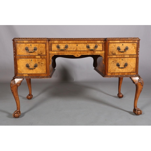 385 - AN 18TH CENTURY-STYLE FIGURED WALNUT DESK, inverted breakfront, having three incised leather panels,... 